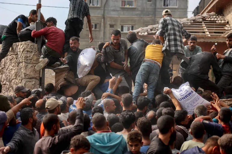 فلسطينيون يتزاحمون على موقع لتوزيع المساعدات في دير البلح وسط قطاع غزة (الفرنسية)