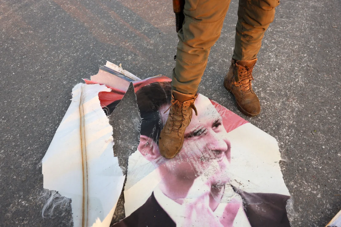مقاتل معارض يخطو على صورة ممزقة للرئيس السوري بشار الأسد في حماة، بعد يوم من احتلال المتمردين على المدينة في 6 ديسمبر 2024. محمد الرفاعي / وكالة الصحافة الفرنسية / جيتي إيماجيس