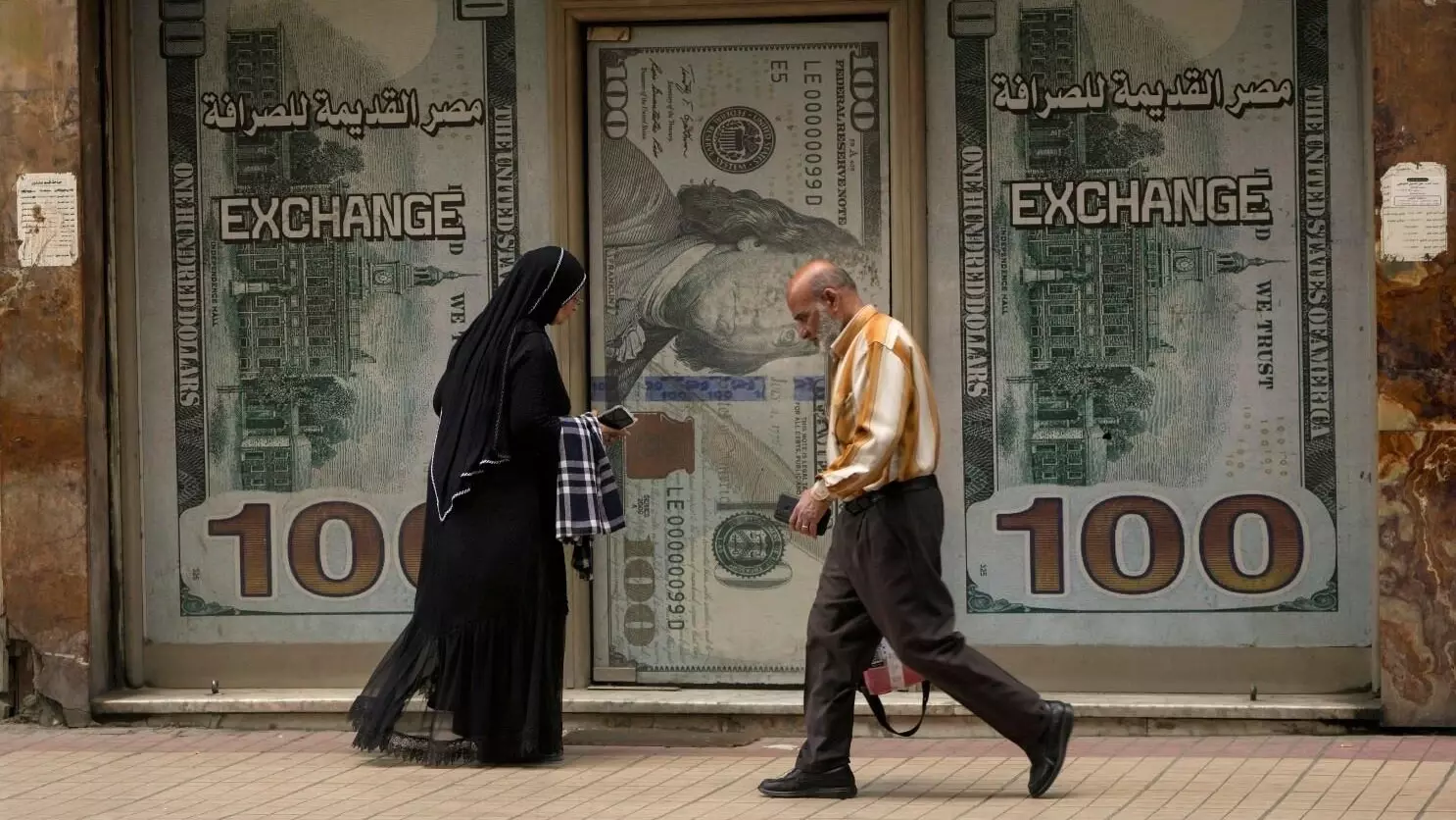 مصريان يسيران في اتجاه معاكس أمام مكتب صرافة (وكالات)